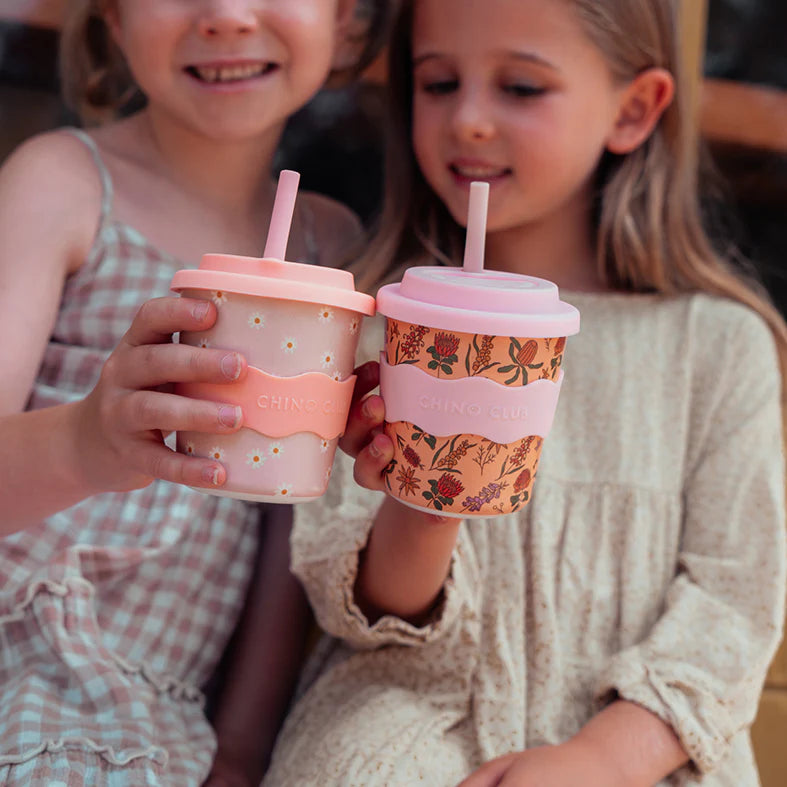 Two pink keep cups with silicone lids and straws; one has daisy print, other floral