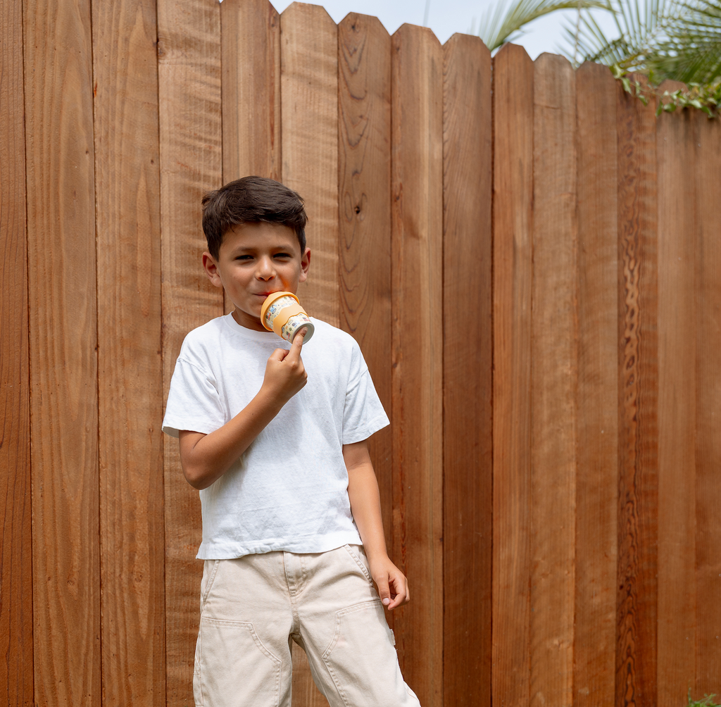 4oz babychino cup held by toddler, toddler sipping outdoors