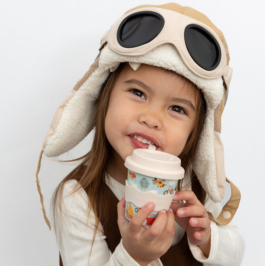 Babychino cup with lid and vehicles print, held by child